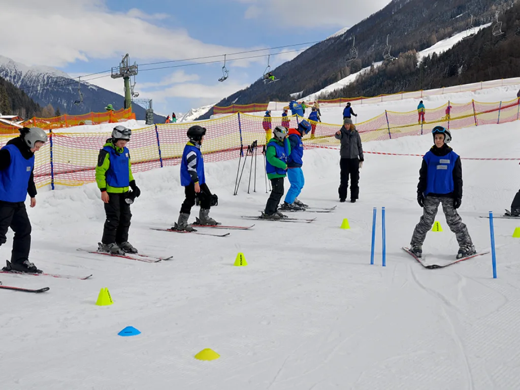 Gruppe steht mit Skiern an der Absperrung des Übungshangs.